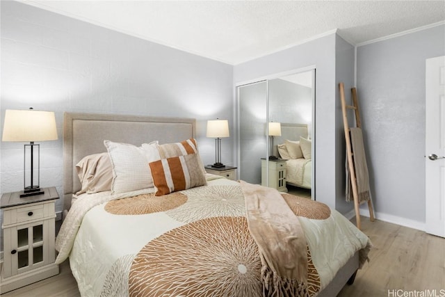 bedroom with a closet, ornamental molding, light hardwood / wood-style flooring, and a textured ceiling