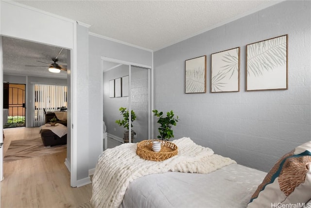 bedroom featuring crown molding, wood-type flooring, and a textured ceiling