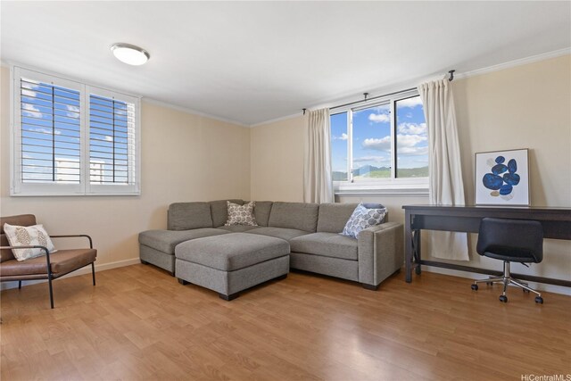 living area with crown molding, light wood-style flooring, and baseboards