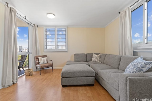 living area with crown molding, light wood-style flooring, and baseboards