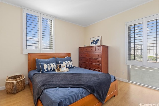 bedroom with crown molding, baseboards, and wood finished floors