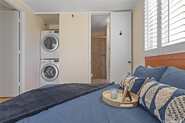 bedroom with connected bathroom and stacked washer and dryer