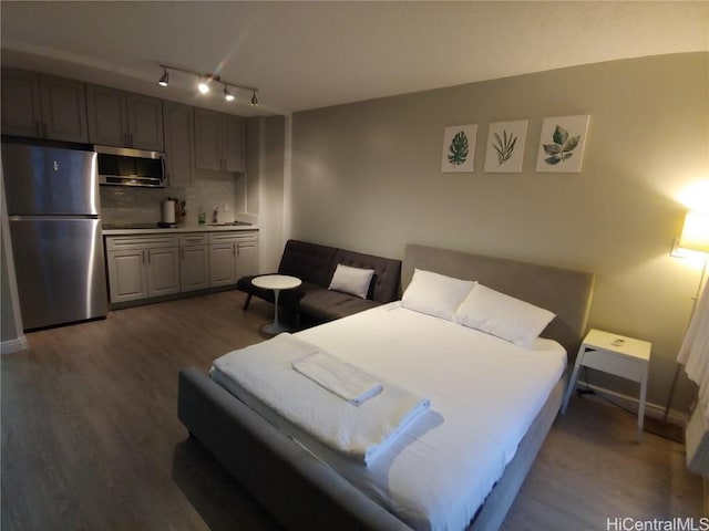 bedroom with sink, dark wood-type flooring, and stainless steel refrigerator