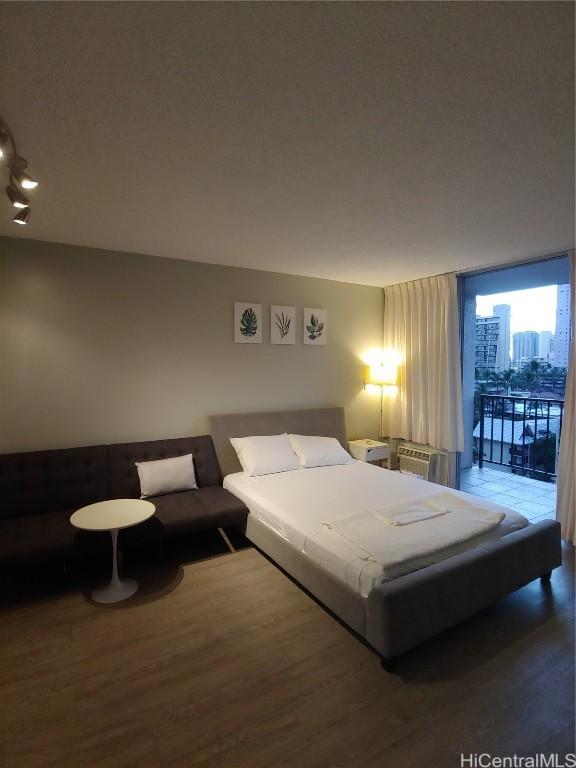 bedroom featuring a wall of windows, hardwood / wood-style floors, and access to outside