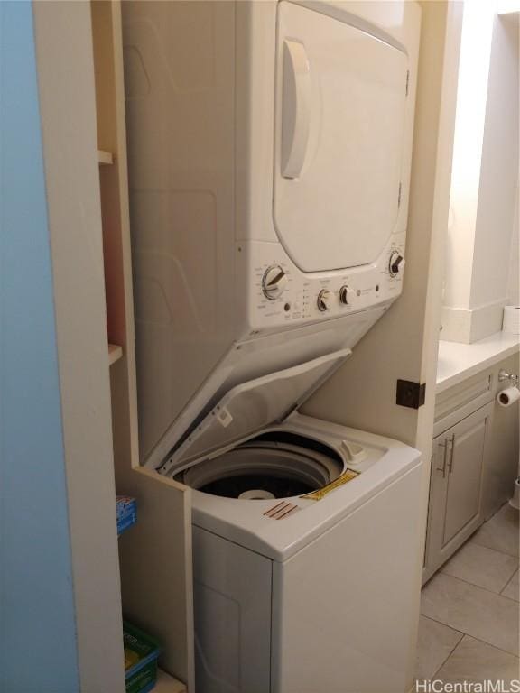 washroom with stacked washer / drying machine and light tile patterned floors