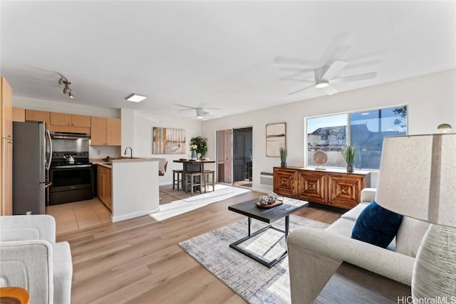 living room with ceiling fan, light hardwood / wood-style floors, and sink