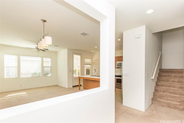 stairway with ceiling fan, carpet floors, and sink