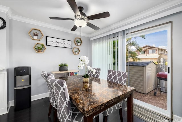 dining room featuring dark wood finished floors, crown molding, baseboards, and ceiling fan