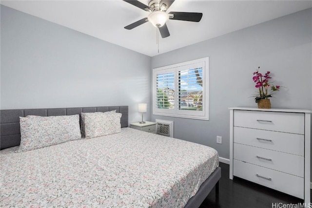 bedroom with a wall unit AC, baseboards, and a ceiling fan