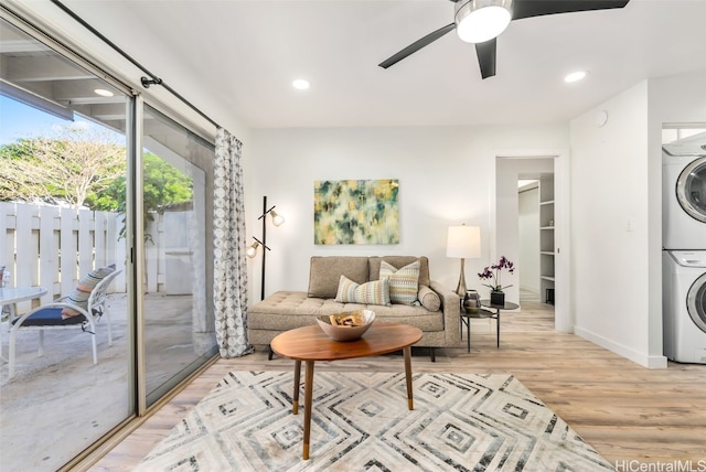 living room featuring ceiling fan, stacked washing maching and dryer, and light wood-type flooring