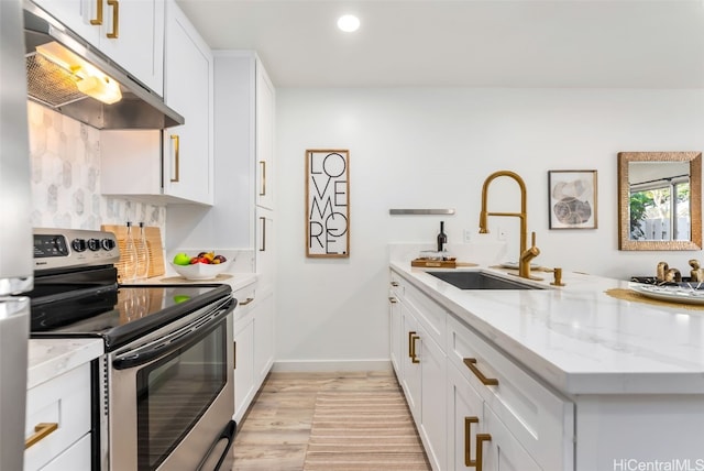 kitchen with kitchen peninsula, light stone counters, stainless steel electric stove, sink, and white cabinetry