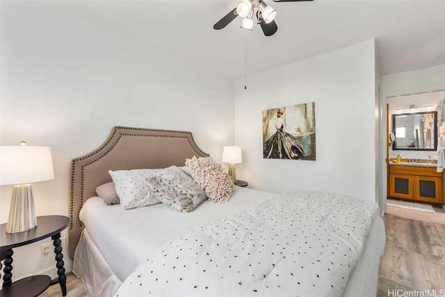 bedroom with ensuite bathroom, light hardwood / wood-style flooring, ceiling fan, and sink