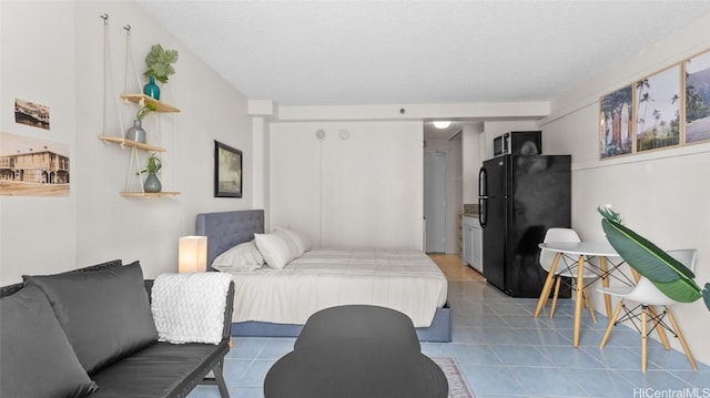 bedroom with black refrigerator and light tile patterned flooring