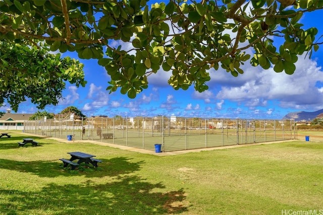 view of home's community with a rural view, a lawn, and tennis court