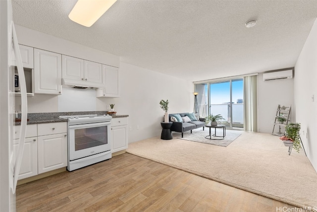 kitchen with white range with electric stovetop, expansive windows, white cabinetry, and a wall unit AC