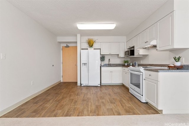 kitchen featuring white cabinets, light hardwood / wood-style floors, white appliances, and a textured ceiling