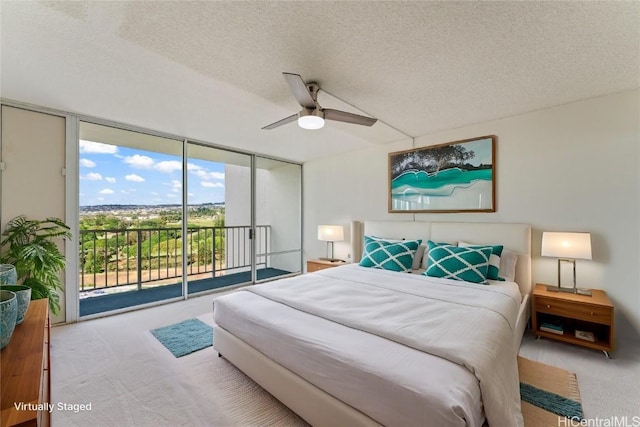 bedroom with access to exterior, ceiling fan, a wall of windows, a textured ceiling, and light carpet