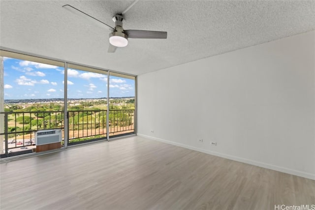 spare room with hardwood / wood-style floors, a textured ceiling, expansive windows, and ceiling fan