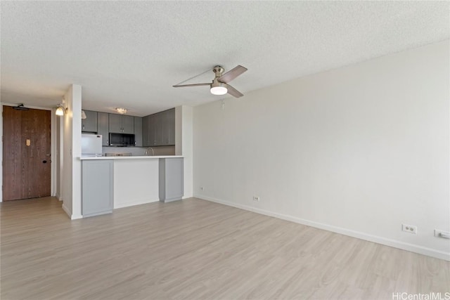 unfurnished living room featuring a textured ceiling, light hardwood / wood-style floors, and ceiling fan