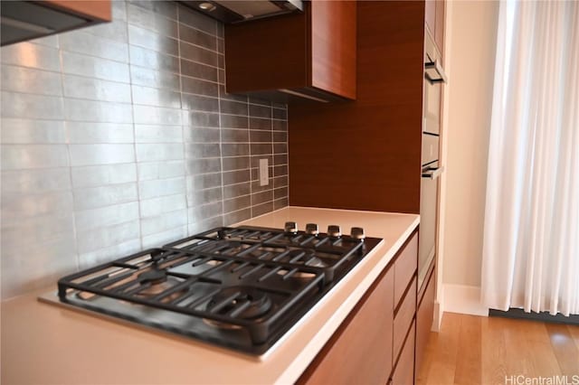 kitchen with backsplash, light hardwood / wood-style flooring, and black gas stovetop