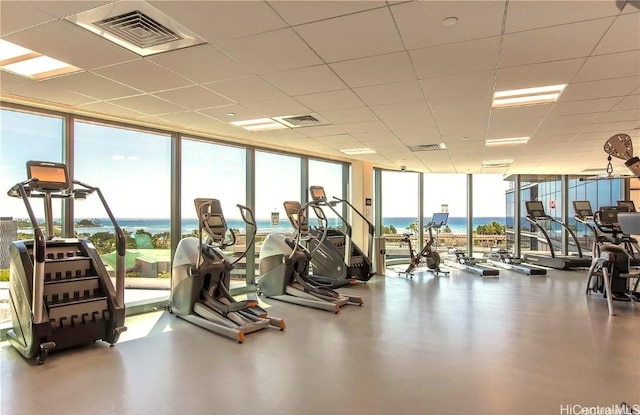 gym with floor to ceiling windows, a wealth of natural light, and a water view