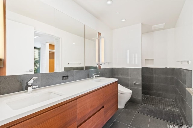 bathroom with vanity, a shower, tile patterned floors, toilet, and tile walls