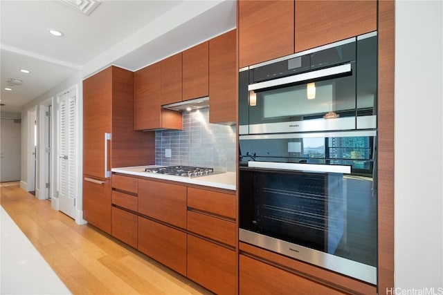 kitchen featuring backsplash, appliances with stainless steel finishes, and light hardwood / wood-style flooring