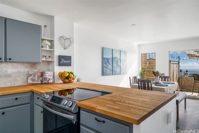 kitchen featuring tasteful backsplash, butcher block counters, and stainless steel electric stove