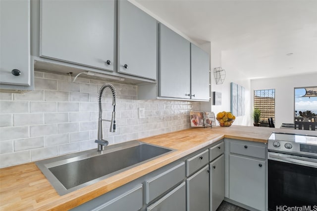 kitchen featuring decorative backsplash, sink, wooden counters, and stainless steel range with electric stovetop