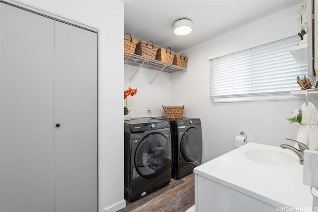 clothes washing area with dark wood-type flooring, sink, and washing machine and clothes dryer