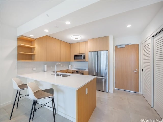 kitchen with light brown cabinets, a kitchen breakfast bar, sink, kitchen peninsula, and stainless steel appliances