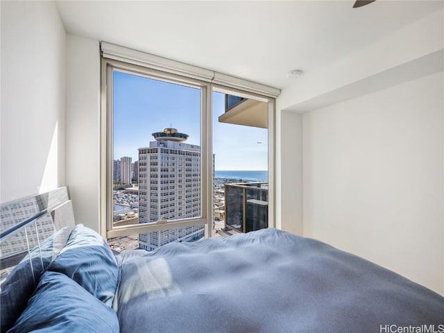 bedroom with ceiling fan, floor to ceiling windows, a water view, and multiple windows