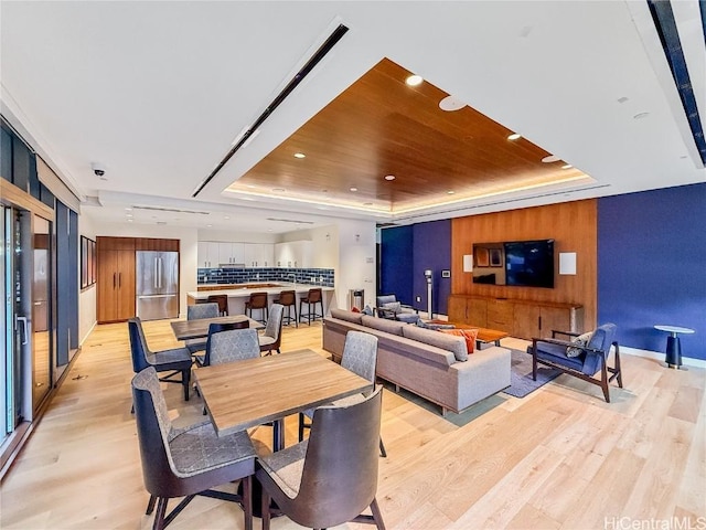 dining room with a tray ceiling, light hardwood / wood-style flooring, and wooden ceiling