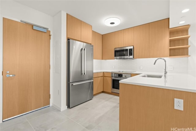 kitchen featuring light brown cabinets, stainless steel appliances, decorative backsplash, sink, and kitchen peninsula