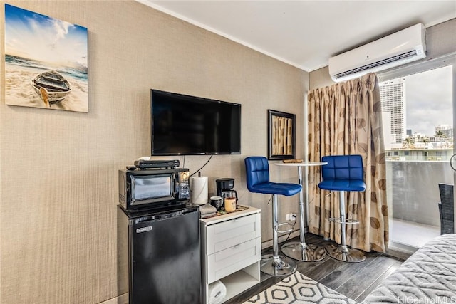 bedroom featuring a wall unit AC and fridge