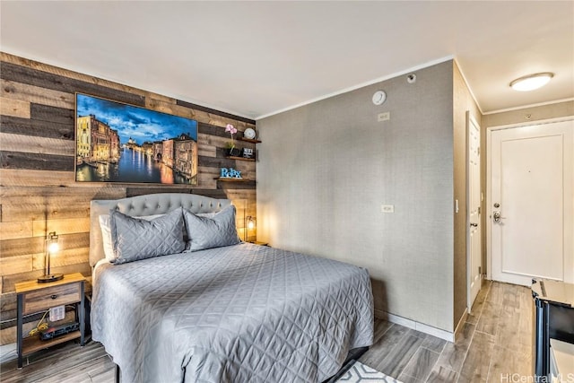 bedroom with hardwood / wood-style floors, crown molding, and wooden walls