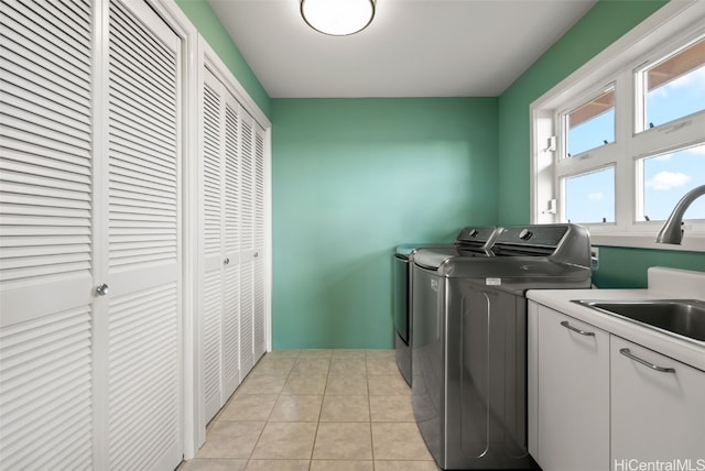 washroom with light tile patterned flooring, cabinets, sink, and washing machine and dryer