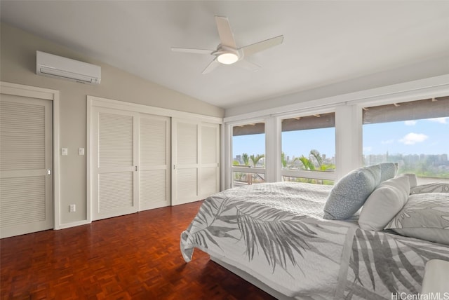 bedroom with ceiling fan, dark parquet floors, a wall mounted AC, lofted ceiling, and two closets