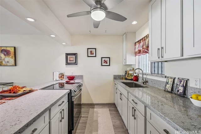 kitchen with light stone countertops, sink, white cabinets, and stainless steel range with electric stovetop