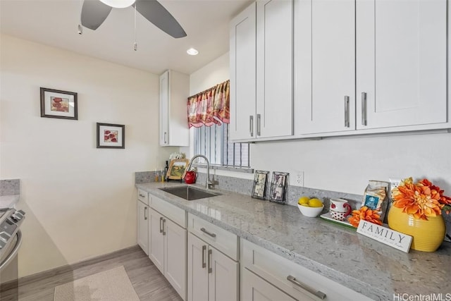 kitchen featuring light stone counters, sink, white cabinetry, and light hardwood / wood-style floors