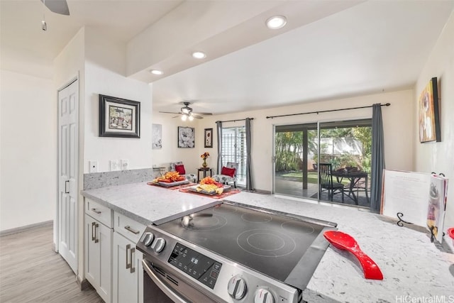 kitchen featuring light hardwood / wood-style floors, stainless steel range with electric stovetop, white cabinets, kitchen peninsula, and light stone counters