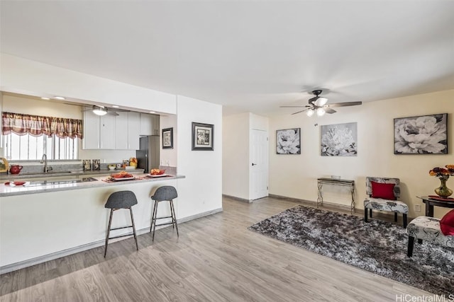 kitchen with a kitchen breakfast bar, white cabinets, kitchen peninsula, ceiling fan, and stainless steel fridge