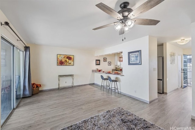 interior space with light hardwood / wood-style floors, stainless steel fridge, kitchen peninsula, and a healthy amount of sunlight