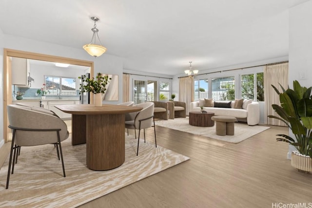 dining space featuring light wood-type flooring and an inviting chandelier