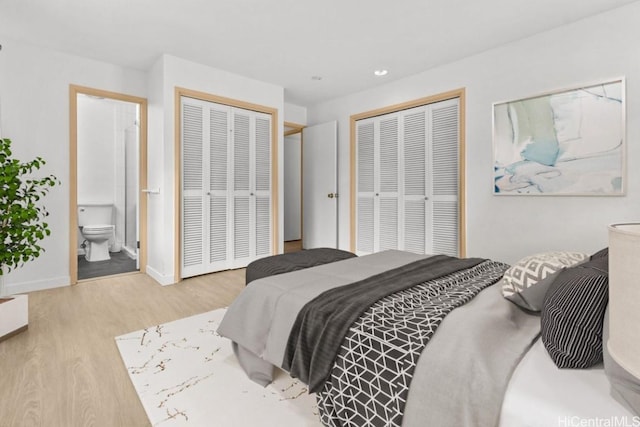 bedroom with connected bathroom, light hardwood / wood-style flooring, and multiple closets