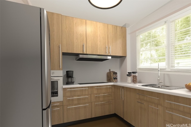 kitchen featuring black electric stovetop, sink, stainless steel refrigerator, and white oven