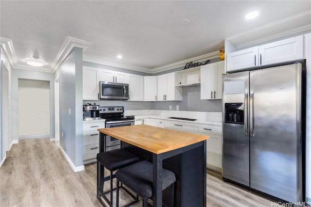 kitchen featuring appliances with stainless steel finishes, a kitchen breakfast bar, ornamental molding, white cabinets, and light hardwood / wood-style floors