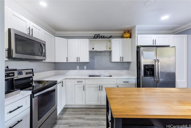 kitchen with light hardwood / wood-style flooring, light stone countertops, ornamental molding, appliances with stainless steel finishes, and white cabinetry