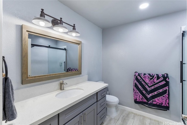 bathroom featuring vanity, toilet, and a shower with door