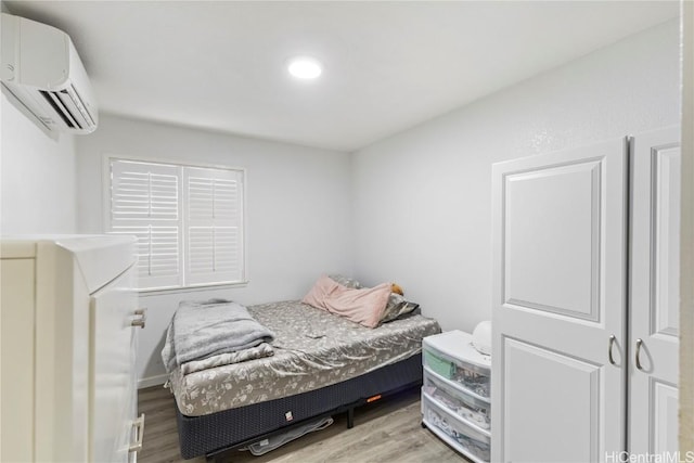 bedroom featuring a wall mounted air conditioner and light wood-type flooring